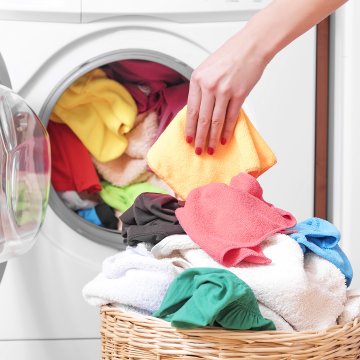 front-load washing machines top-load washers which is better woman hand taking laundry out of the washer basket with colorful clothes